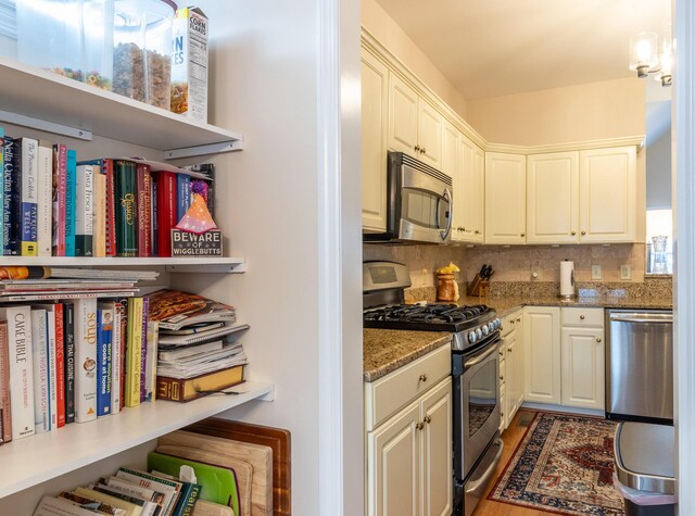 kitchen with white cabinets, stainless steel appliances, stone countertops, and backsplash