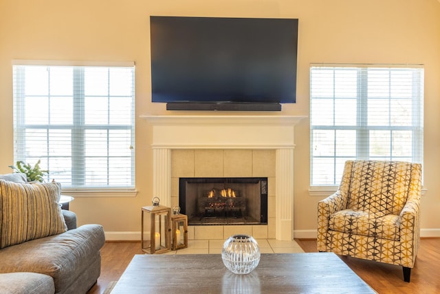 sitting room featuring a tiled fireplace, hardwood / wood-style flooring, and a healthy amount of sunlight