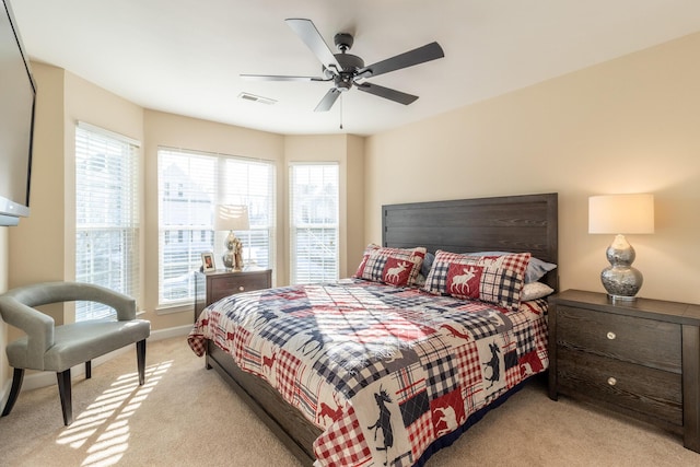 bedroom featuring ceiling fan, multiple windows, and light carpet