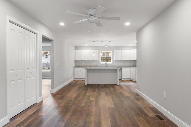 kitchen featuring pendant lighting, ceiling fan, a kitchen island, dark hardwood / wood-style flooring, and white cabinetry