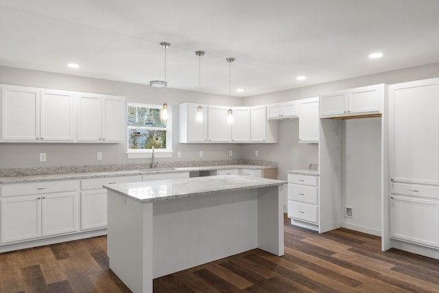 kitchen featuring light stone countertops, sink, pendant lighting, white cabinets, and a center island