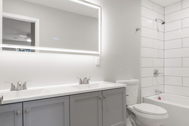 full bathroom featuring tiled shower / bath, vanity, toilet, and ceiling fan