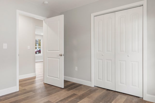 unfurnished bedroom with dark hardwood / wood-style flooring and a closet