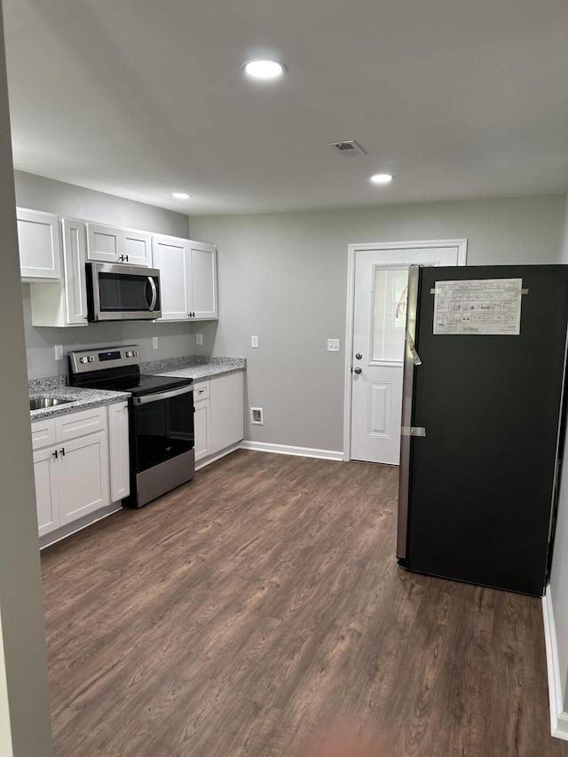 kitchen with light stone counters, white cabinetry, and stainless steel appliances