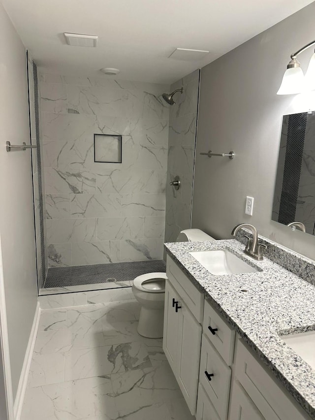 bathroom with tiled shower, vanity, and toilet