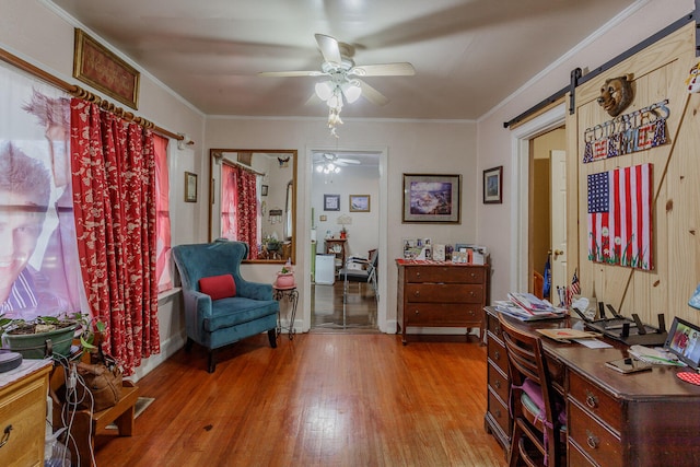 sitting room with ceiling fan, a barn door, ornamental molding, and light hardwood / wood-style flooring