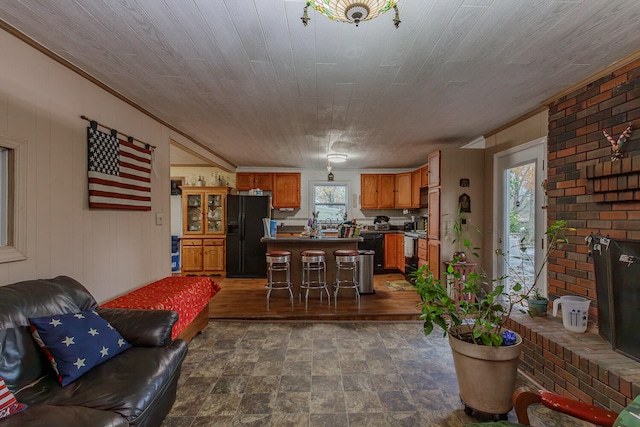 living room with a brick fireplace, wooden walls, and crown molding