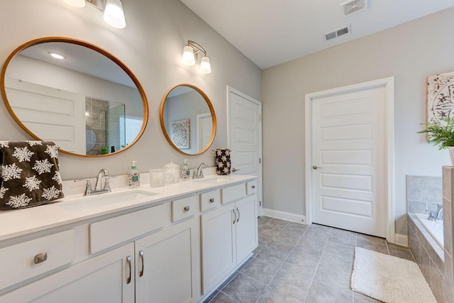 bathroom with tile patterned flooring, vanity, and tiled tub