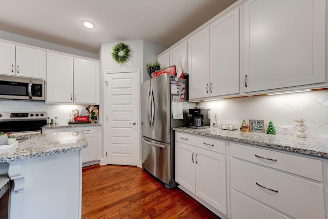 kitchen with white cabinets, appliances with stainless steel finishes, dark hardwood / wood-style flooring, and tasteful backsplash