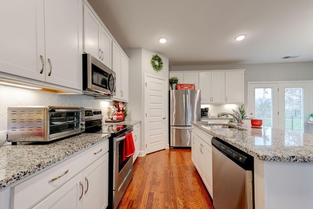 kitchen featuring white cabinetry, sink, a kitchen island with sink, appliances with stainless steel finishes, and light wood-type flooring