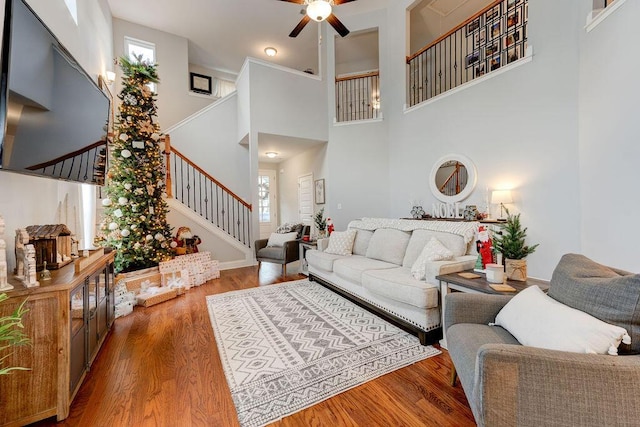 living room featuring a high ceiling, ceiling fan, and wood-type flooring