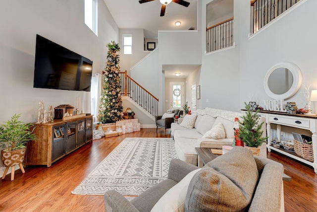 living room with hardwood / wood-style floors, a towering ceiling, and ceiling fan