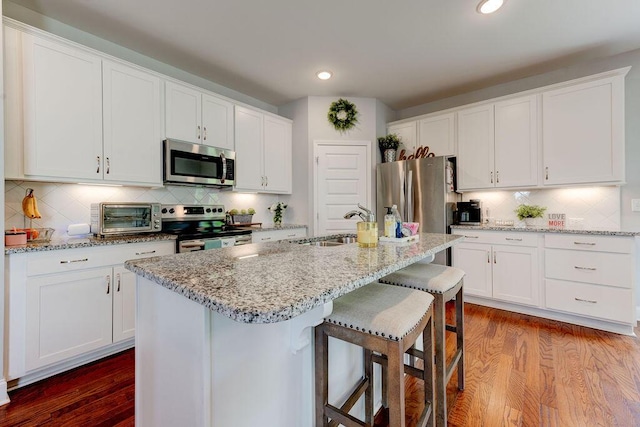 1494 Buttonwood, Chattanooga, TN 37421 - kitchen with appliances with stainless steel finishes, decorative backsplash, dark wood-type flooring, white cabinets, and a kitchen bar