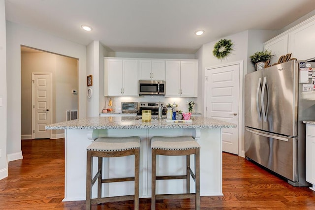 1494 Buttonwood, Chattanooga, TN 37421 - kitchen featuring appliances with stainless steel finishes, a kitchen bar, light stone countertops, white cabinetry, and decorative backsplash