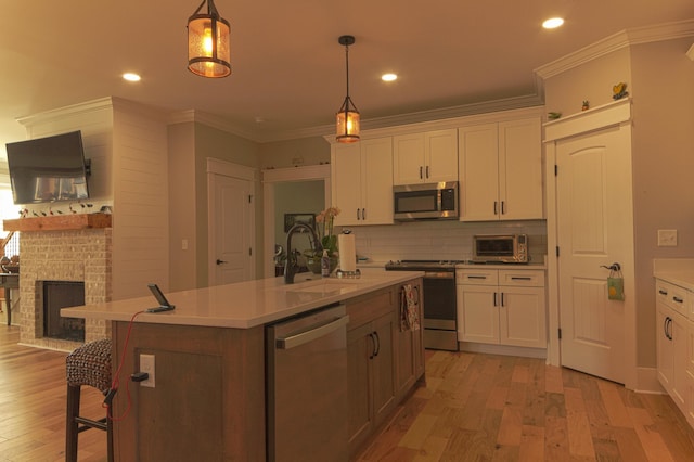 kitchen featuring light wood-type flooring, white cabinetry, stainless steel appliances, and a kitchen island with sink