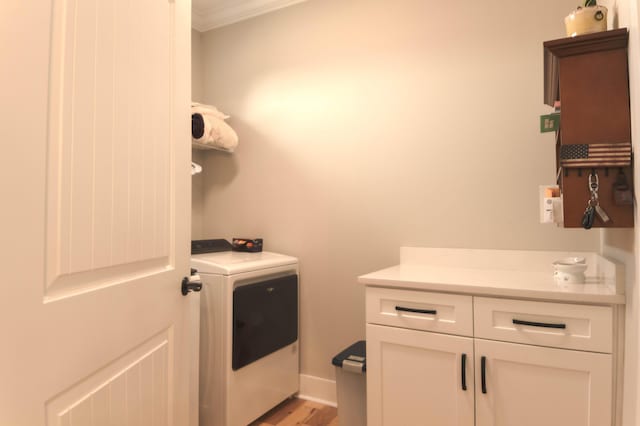 washroom featuring cabinets, washer / clothes dryer, ornamental molding, and light hardwood / wood-style floors