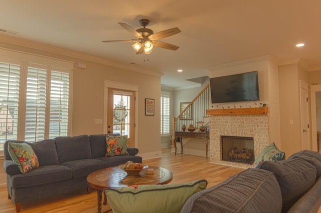 living room with ceiling fan, a fireplace, light wood-type flooring, and crown molding