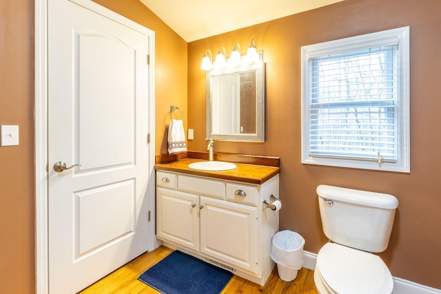 bathroom with vaulted ceiling, toilet, hardwood / wood-style flooring, and vanity