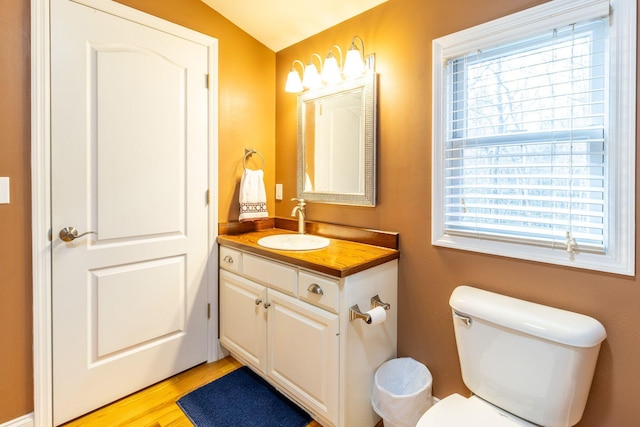 bathroom with lofted ceiling, vanity, a wealth of natural light, and toilet