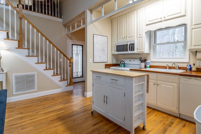 kitchen featuring white cabinetry, sink, wooden counters, and white appliances