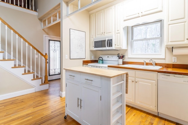 kitchen with butcher block countertops, sink, white appliances, and white cabinetry