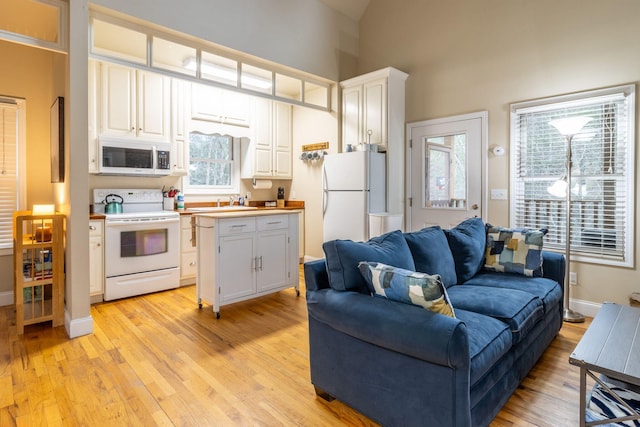 kitchen with white appliances, white cabinets, and light hardwood / wood-style flooring