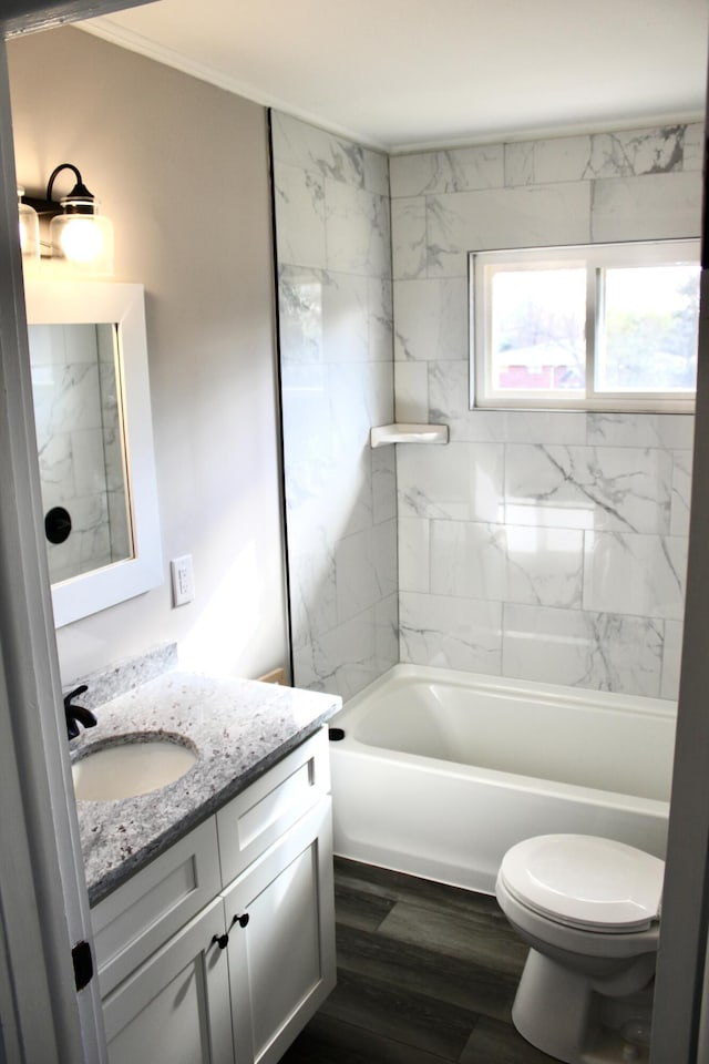 full bathroom featuring tiled shower / bath combo, vanity, crown molding, hardwood / wood-style floors, and toilet