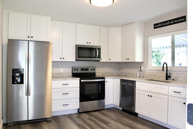 kitchen featuring light stone countertops, sink, dark hardwood / wood-style floors, white cabinets, and appliances with stainless steel finishes