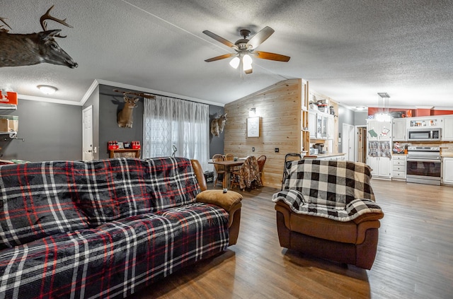 living room with ceiling fan, crown molding, a textured ceiling, wooden walls, and light wood-type flooring