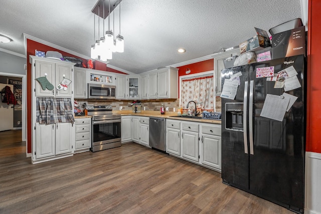 kitchen featuring hanging light fixtures, dark hardwood / wood-style floors, ornamental molding, white cabinetry, and stainless steel appliances