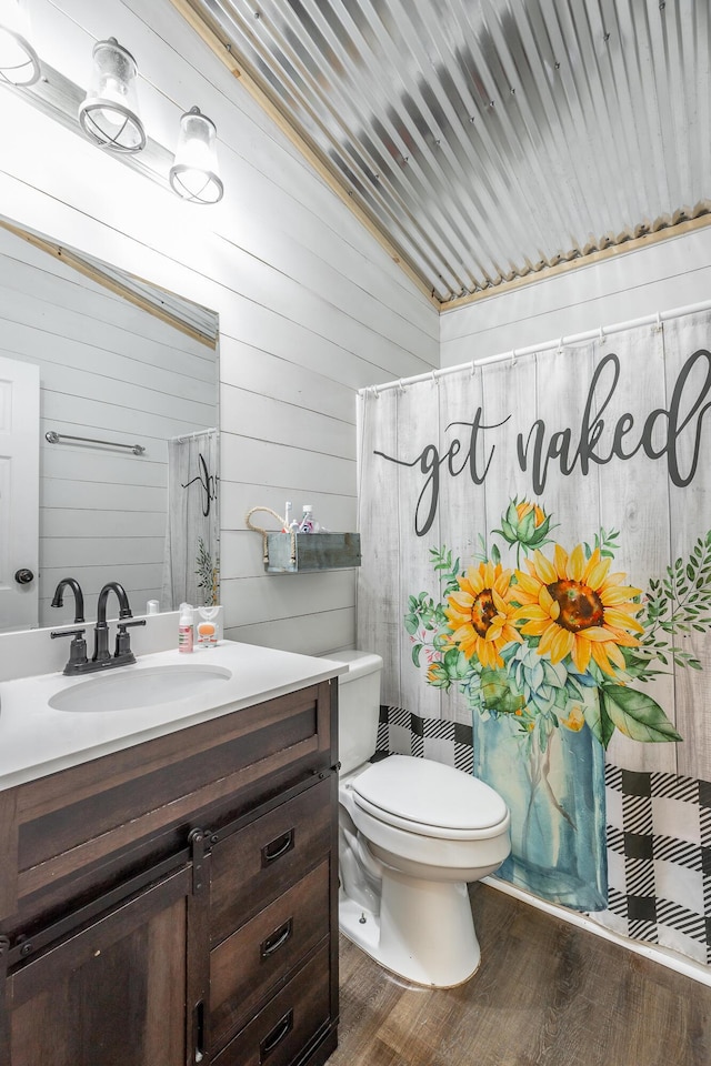 bathroom featuring wood walls, vanity, wood-type flooring, and toilet