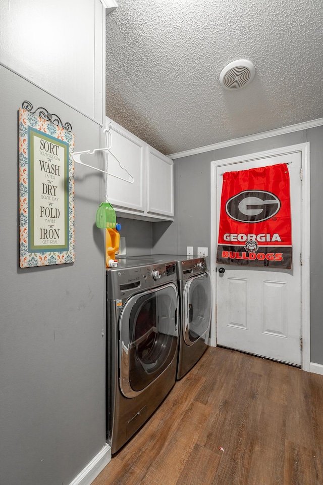 washroom with cabinets, washing machine and dryer, dark hardwood / wood-style floors, crown molding, and a textured ceiling