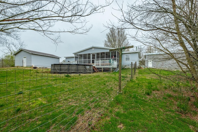 rear view of property featuring a pool, a lawn, and a sunroom