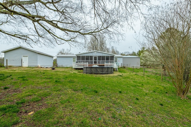 rear view of house featuring a yard, a sunroom, and a swimming pool