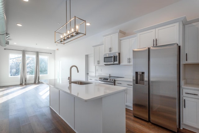 kitchen with white cabinets, appliances with stainless steel finishes, a center island with sink, and sink