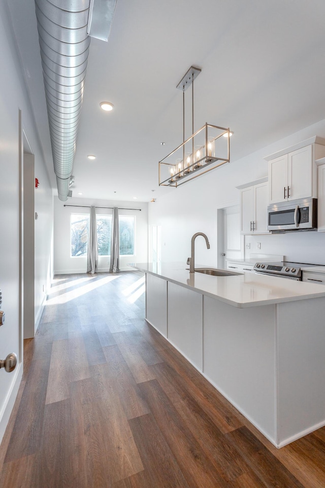 kitchen featuring dark wood-type flooring, white cabinets, hanging light fixtures, sink, and appliances with stainless steel finishes