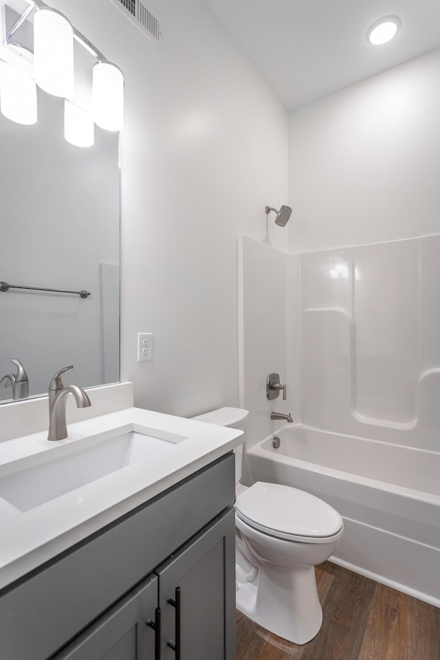 full bathroom featuring vanity, hardwood / wood-style floors, washtub / shower combination, and toilet