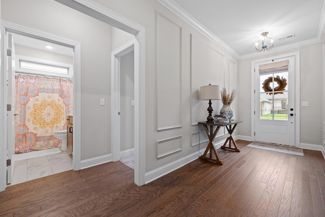 foyer with a chandelier, dark wood-type flooring, and ornamental molding