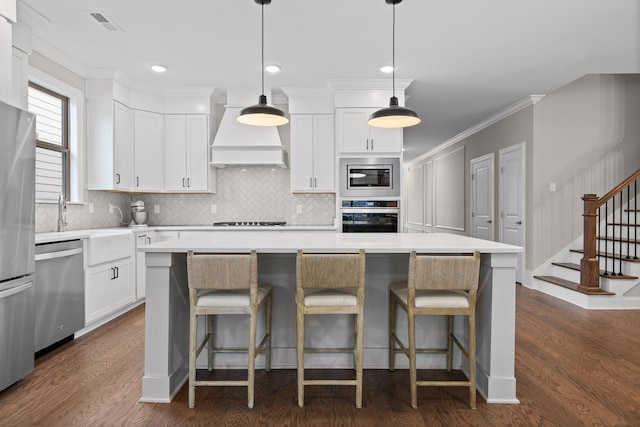 kitchen featuring white cabinets, a kitchen island, custom exhaust hood, and appliances with stainless steel finishes