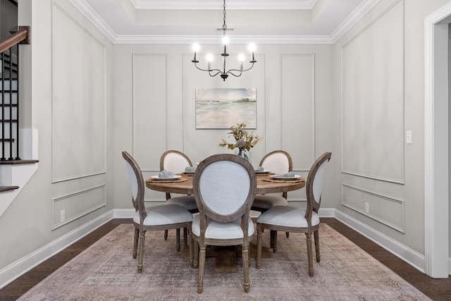 dining space featuring a tray ceiling, dark hardwood / wood-style flooring, ornamental molding, and a notable chandelier