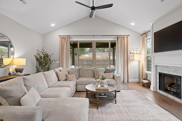 living room with wood-type flooring, a brick fireplace, ceiling fan, and lofted ceiling