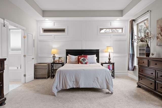 bedroom featuring light colored carpet and ensuite bath