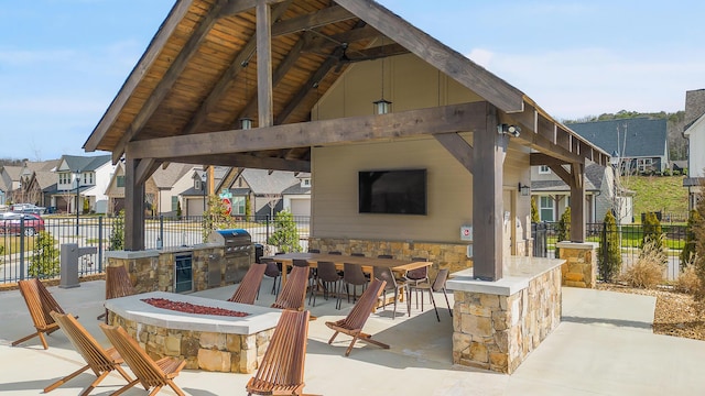 view of patio / terrace featuring grilling area, a gazebo, a bar, exterior kitchen, and an outdoor fire pit