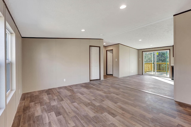 empty room featuring crown molding, a textured ceiling, and light wood-type flooring