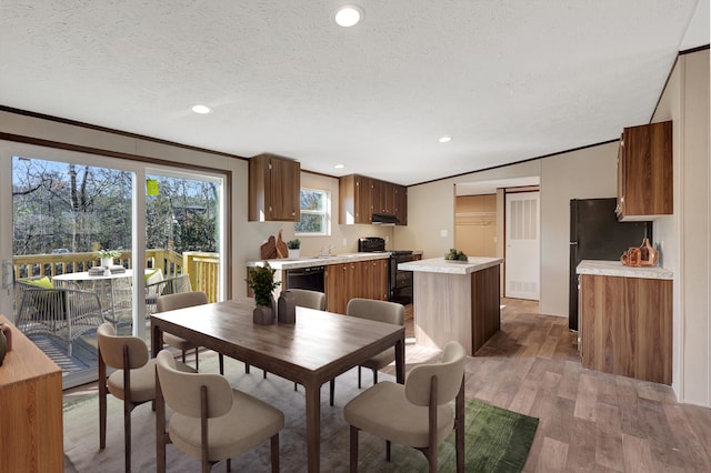 dining area featuring crown molding, light hardwood / wood-style floors, and a textured ceiling