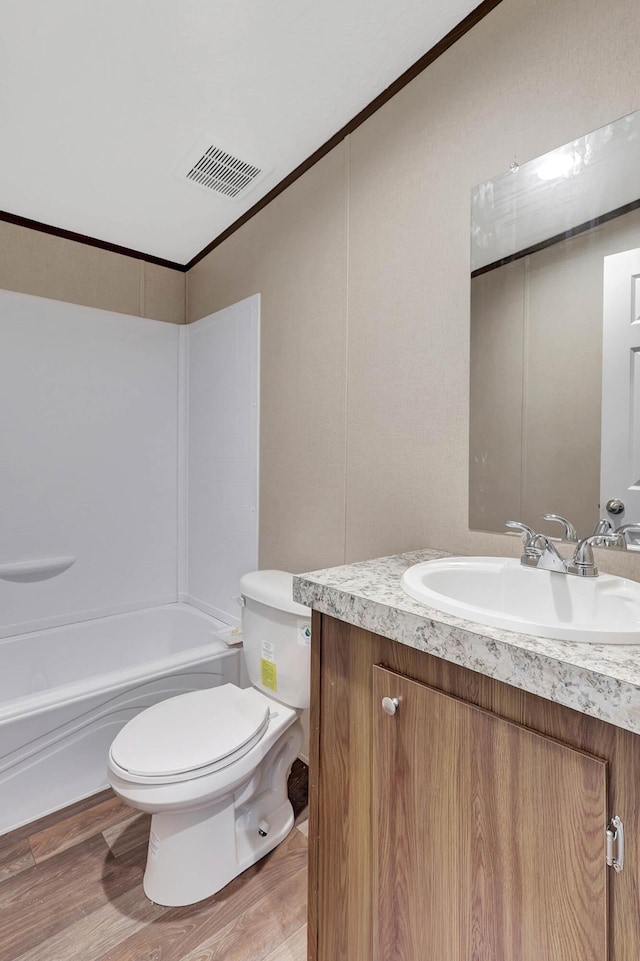 full bathroom with crown molding, vanity, wood-type flooring, shower / bathtub combination, and toilet