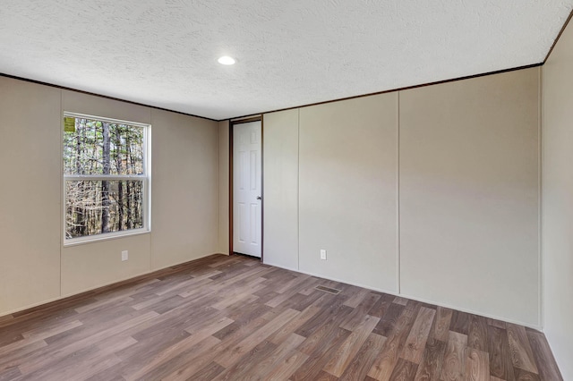 unfurnished bedroom featuring wood-type flooring, a textured ceiling, and a closet