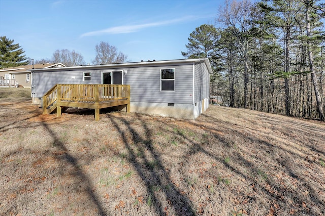 back of property featuring a wooden deck and a lawn