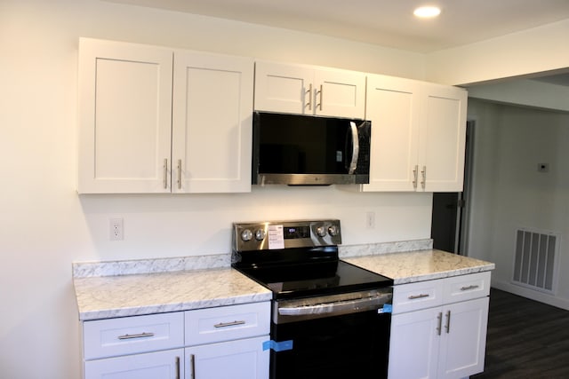 kitchen featuring light stone countertops, white cabinetry, dark wood-type flooring, and appliances with stainless steel finishes