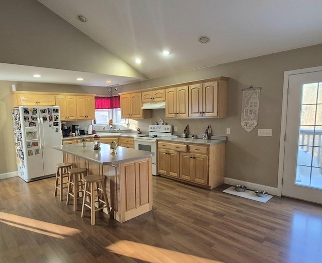 kitchen featuring white appliances, a healthy amount of sunlight, a center island, and a kitchen bar